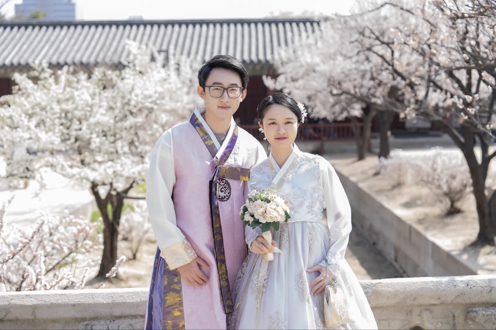 A visiting couple photographed with spring blossoms and palace architecture at Changgyeonggung