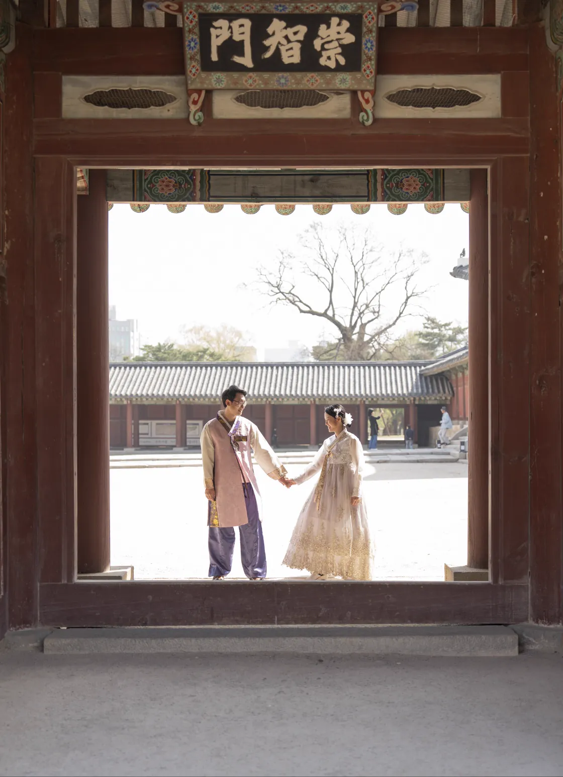 A couple framed by a traditional palace gate during their Seoul photo session