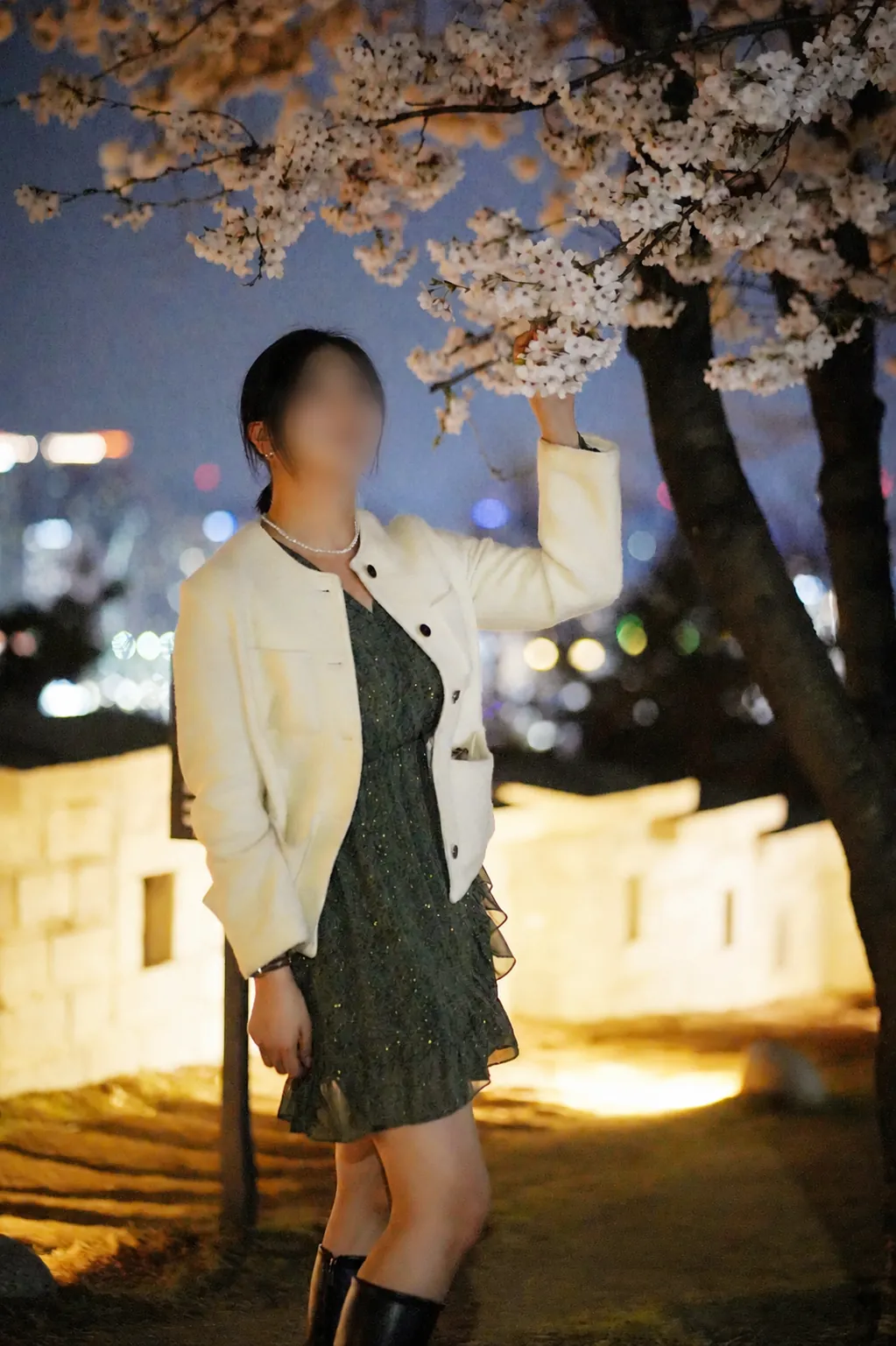 A privacy-blurred spring portrait beneath cherry blossoms at Naksan Park