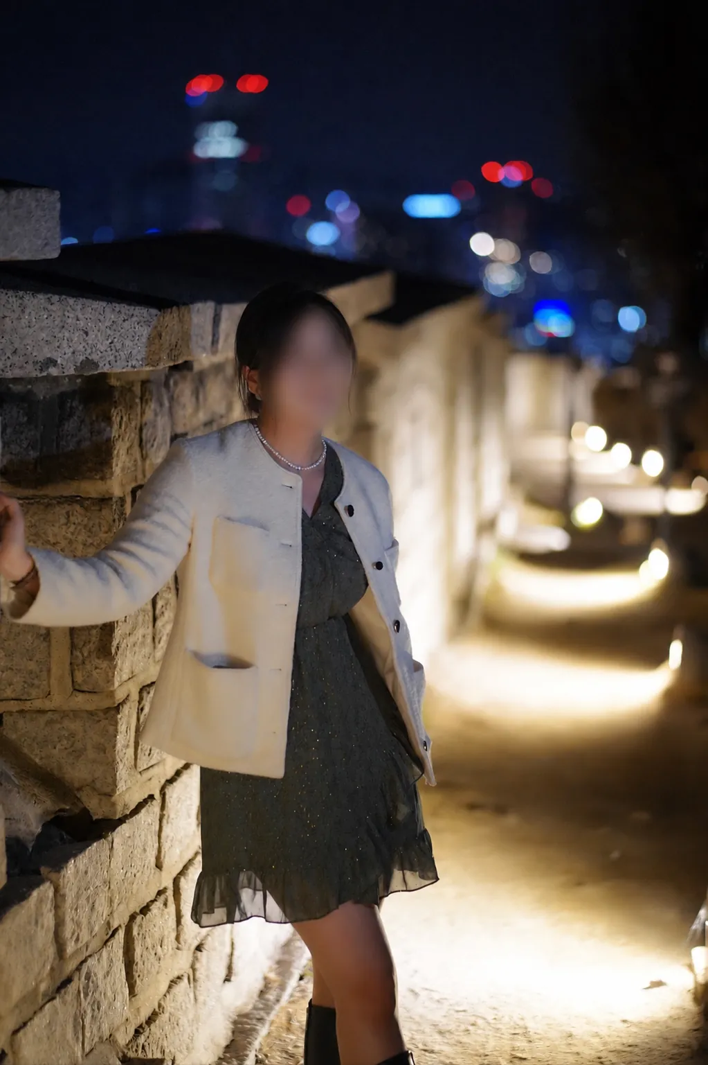 A privacy-blurred portrait with the Seoul City Wall and night skyline at Naksan Park